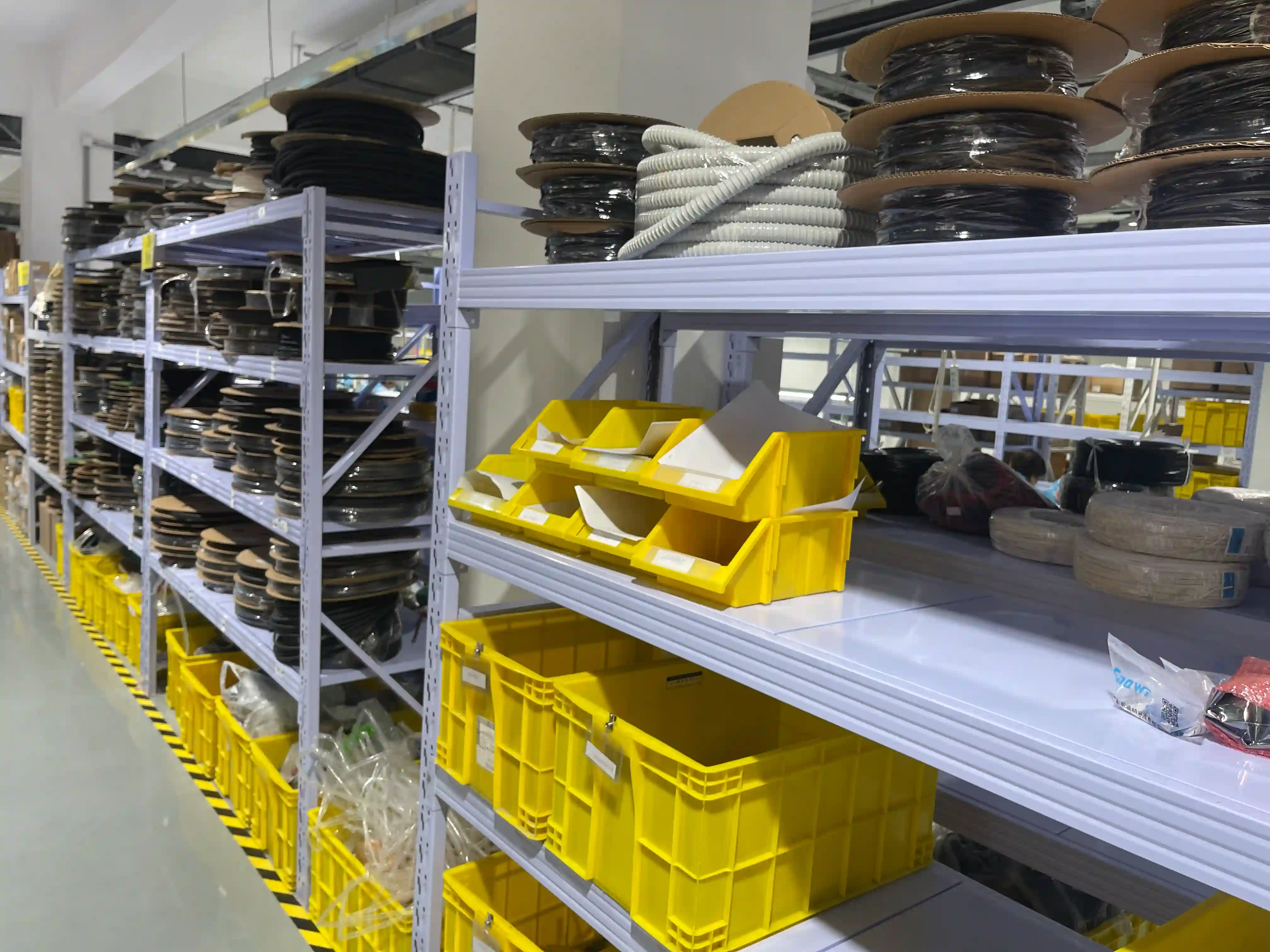 Hyller med materialspoler, deler og gule kasser